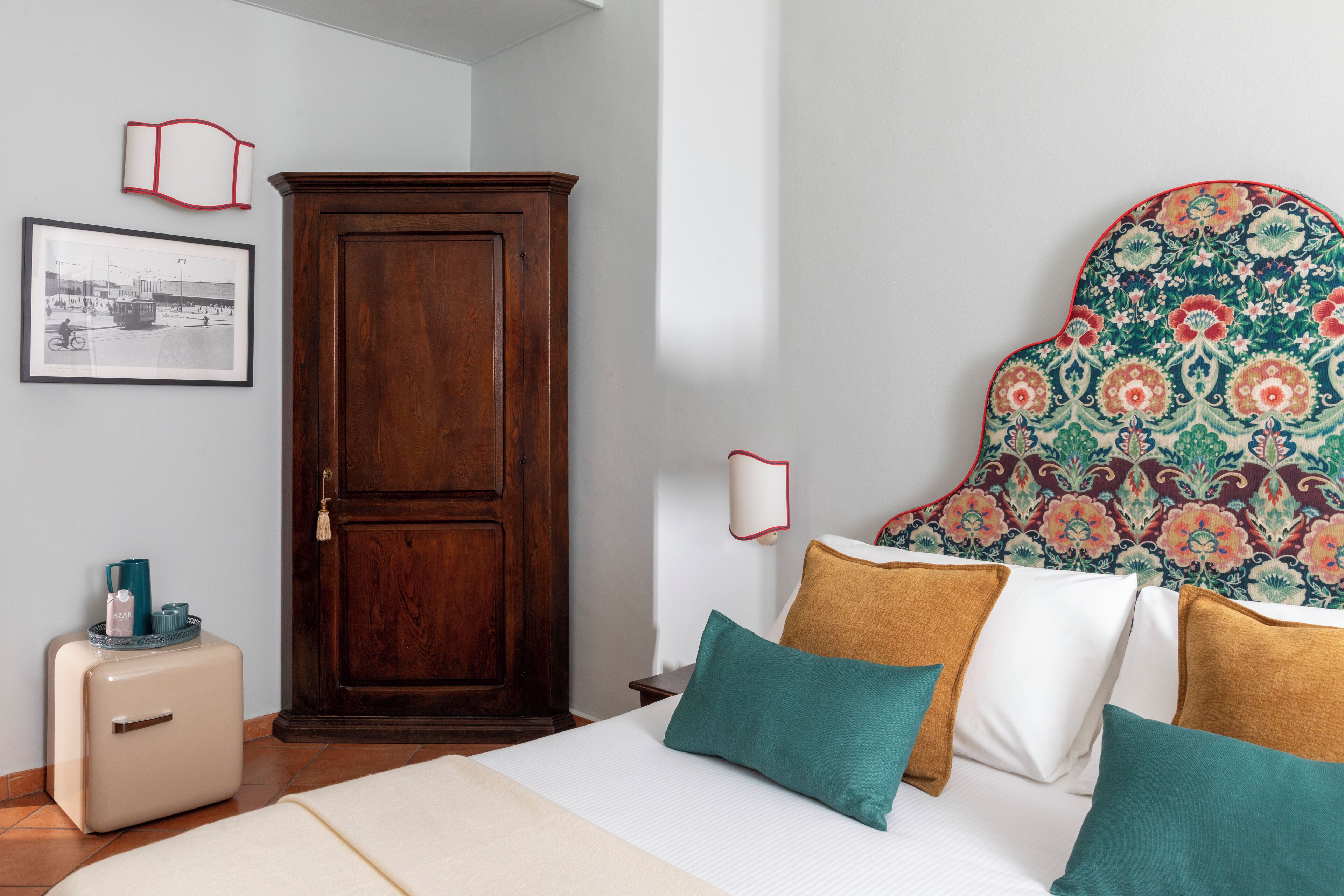 Ein Schlafzimmer mit Bett, Kleiderschrank, kleinem Tisch mit Wasserkocher und einem gerahmten Bild an der Wand.