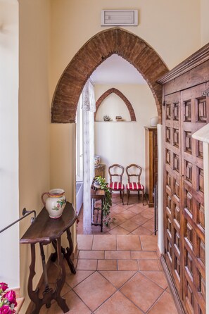 Stroll through this charming corridor, featuring a traditional wooden door and a cozy seating area with a view of the outdoors.