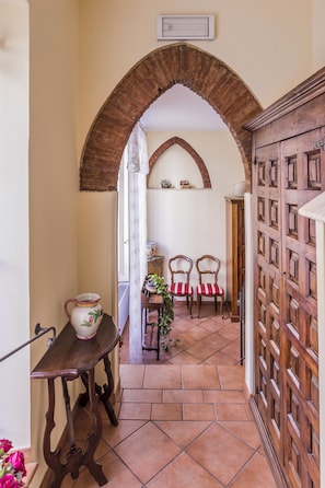 Stroll through this charming corridor, featuring a traditional wooden door and a cozy seating area with a view of the outdoors.