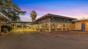 A hotel with a covered outdoor area, a glass facade, and a brick exterior. - Plainsman Motel (Forbes)