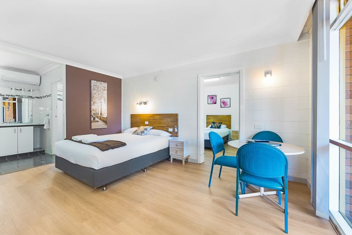 Quarto de hotel moderno com cama, escrivaninha e cadeiras.