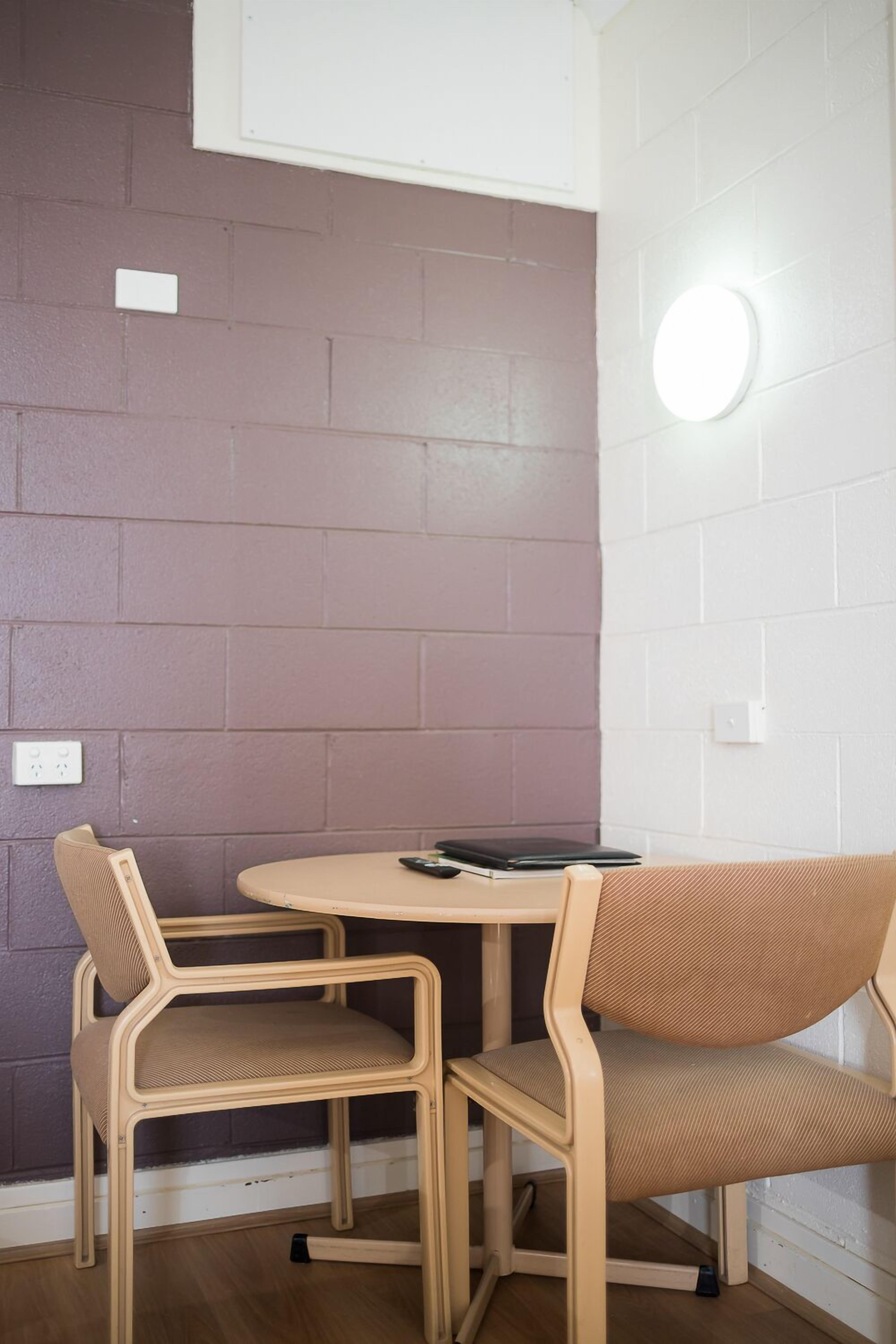 A small, cozy room with a round table and two chairs. The walls are painted in two colors, one dark and one light.