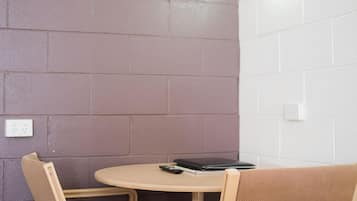 A small, cozy room with a round table and two chairs. The walls are painted in two colors, one dark and one light.