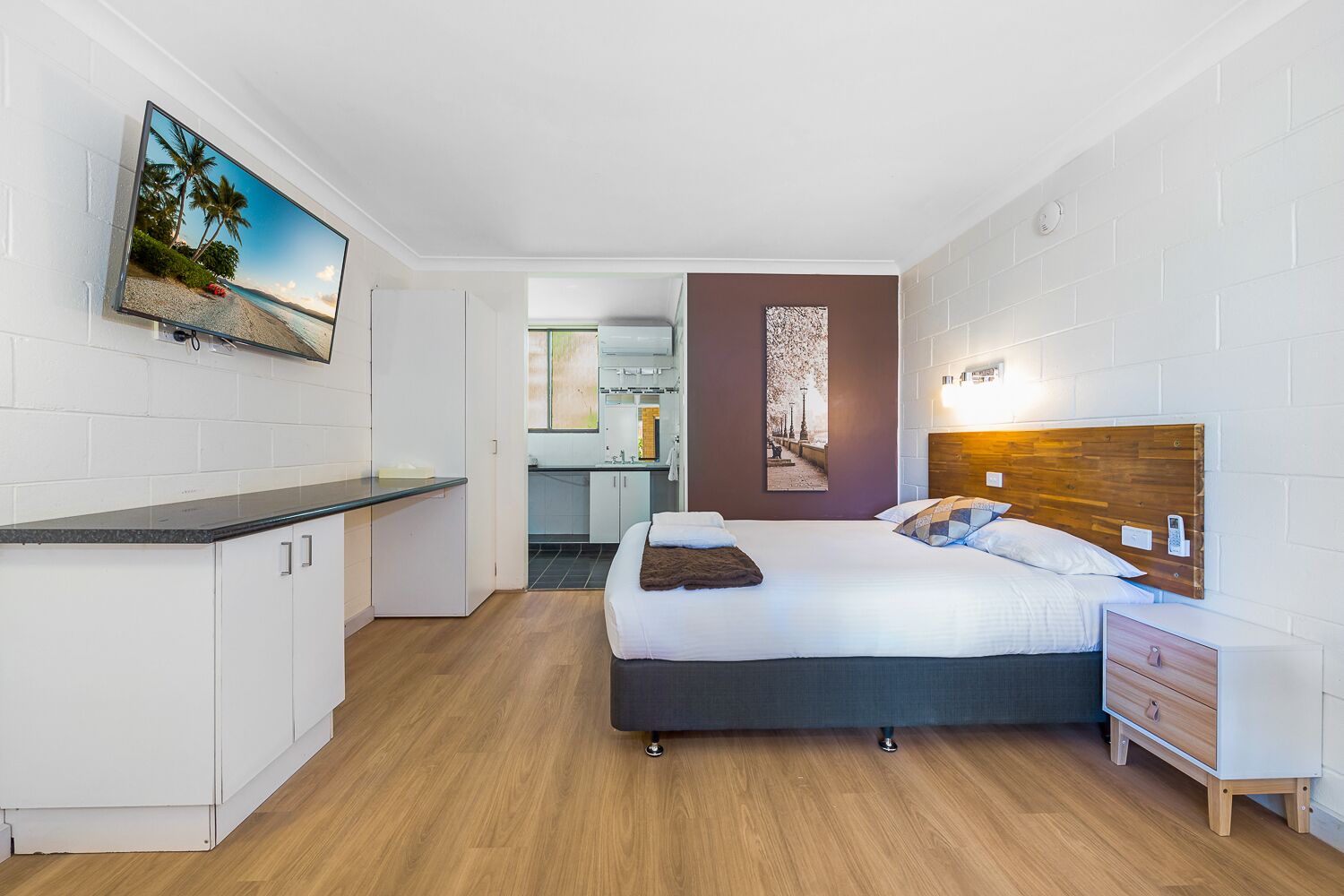 A modern hotel room with a bed, bedside table, and a small desk area.