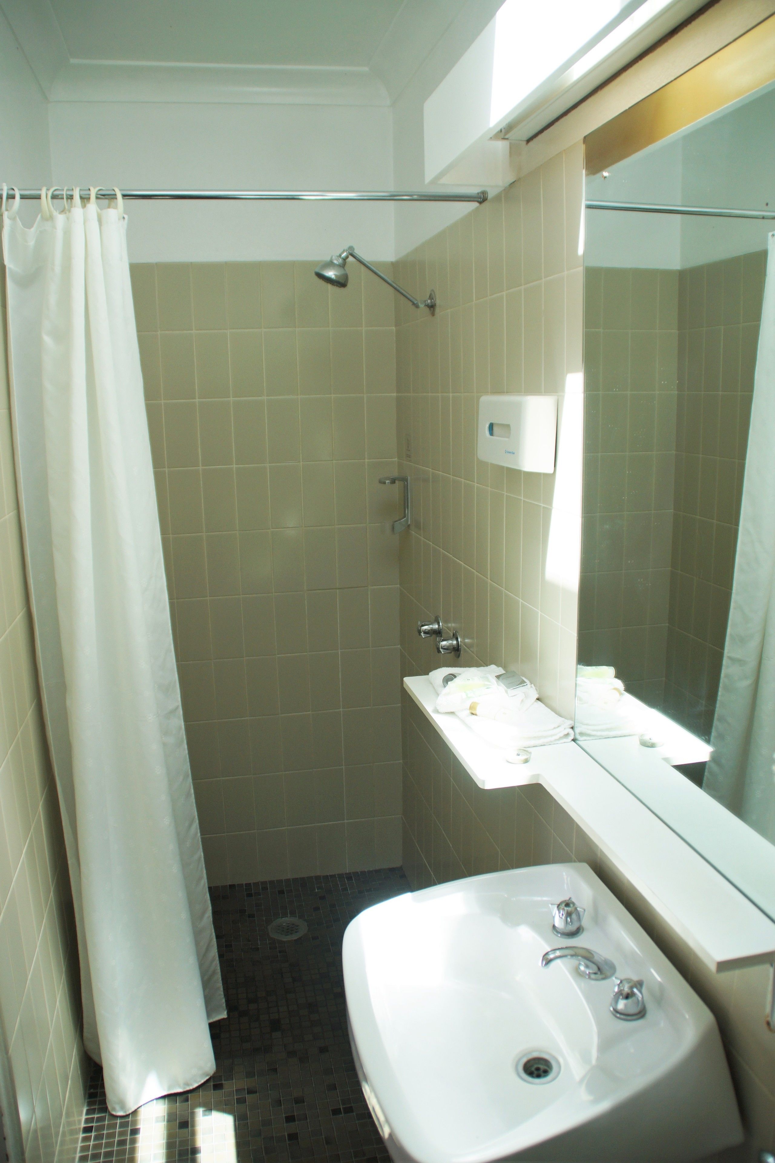 A bathroom with a shower, a sink, and a mirror.