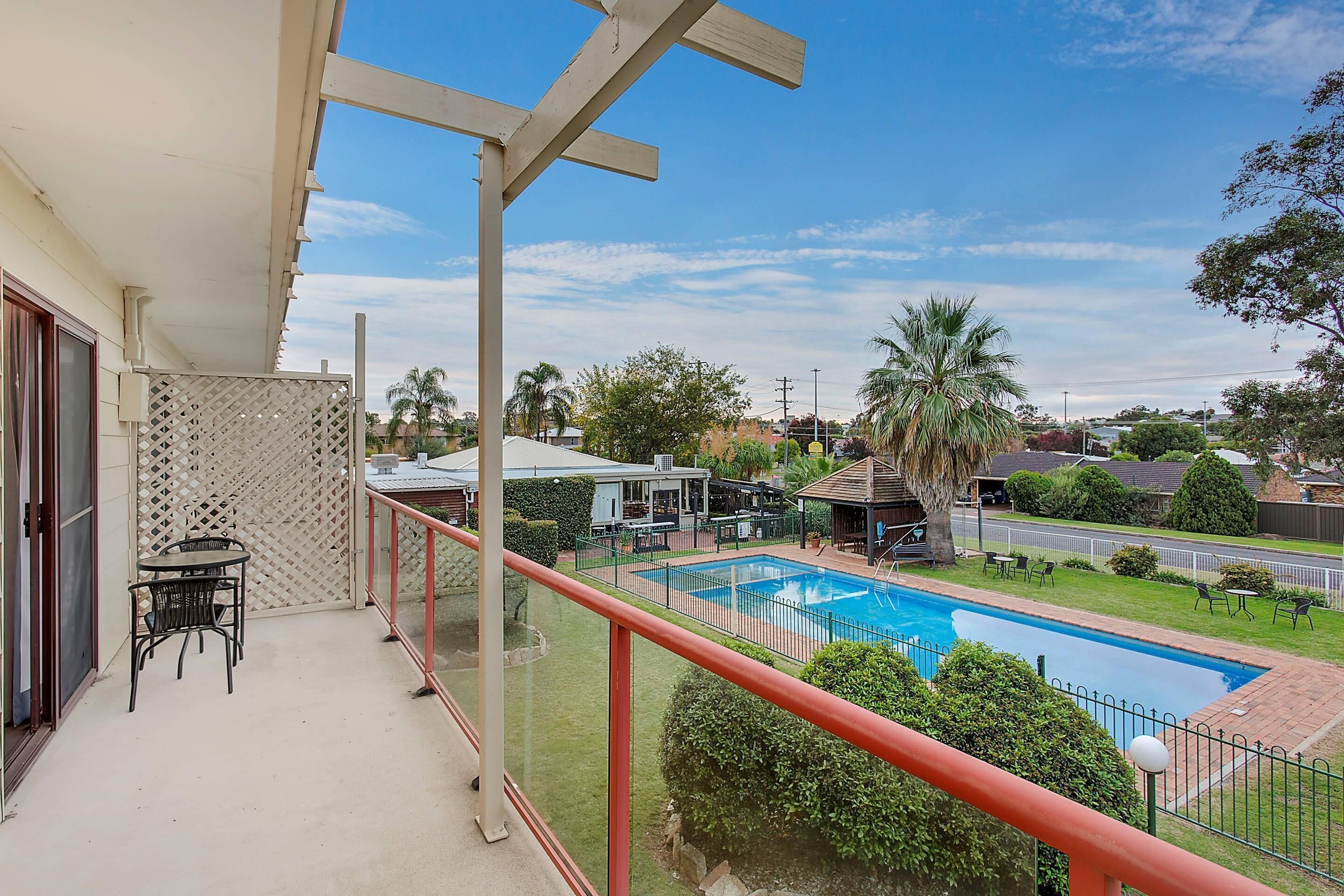 A balcony with a pool, outdoor furniture, and a view of the surrounding neighborhood.