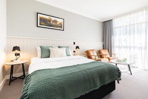 A hotel room with a bed, a chair, a small table, a lamp, and a window with curtains. - Comfort Inn Gateway Tamworth (South Tamworth)