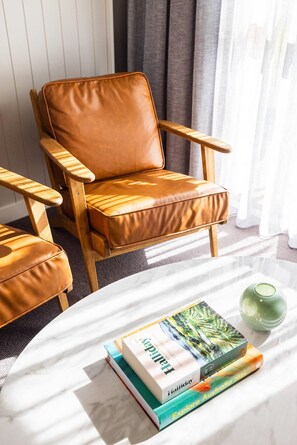 A room with a brown leather chair, a white table with books and a green vase. - Comfort Inn Gateway Tamworth (South Tamworth)