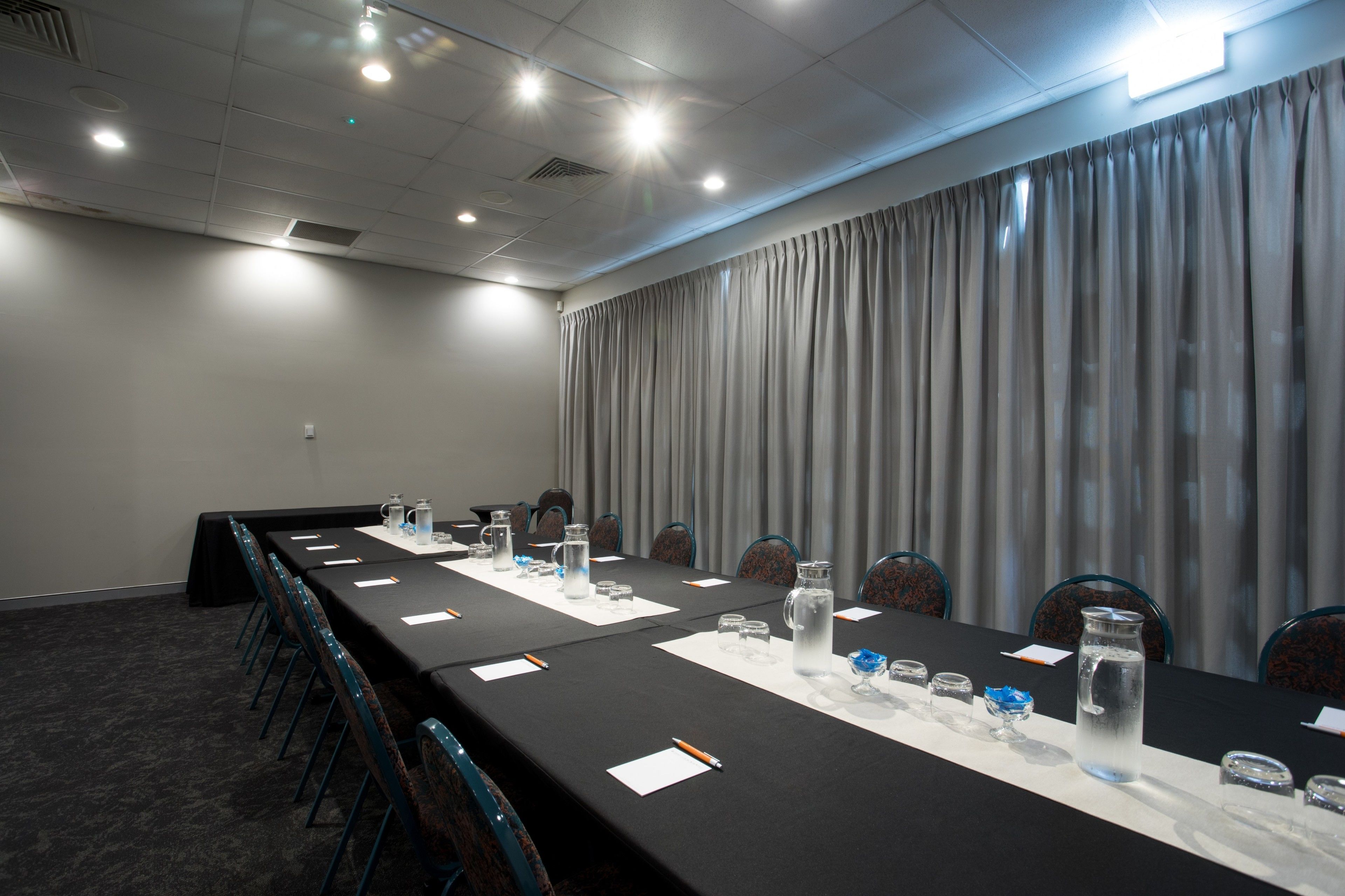 A conference room with a long table, chairs, water bottles, and papers.