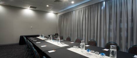 A conference room with a long table, chairs, water bottles, and papers.