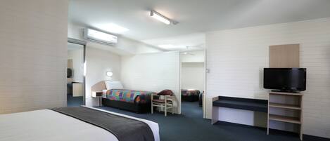 Habitación de hotel con cama, escritorio, silla, televisor y baño a la vista.