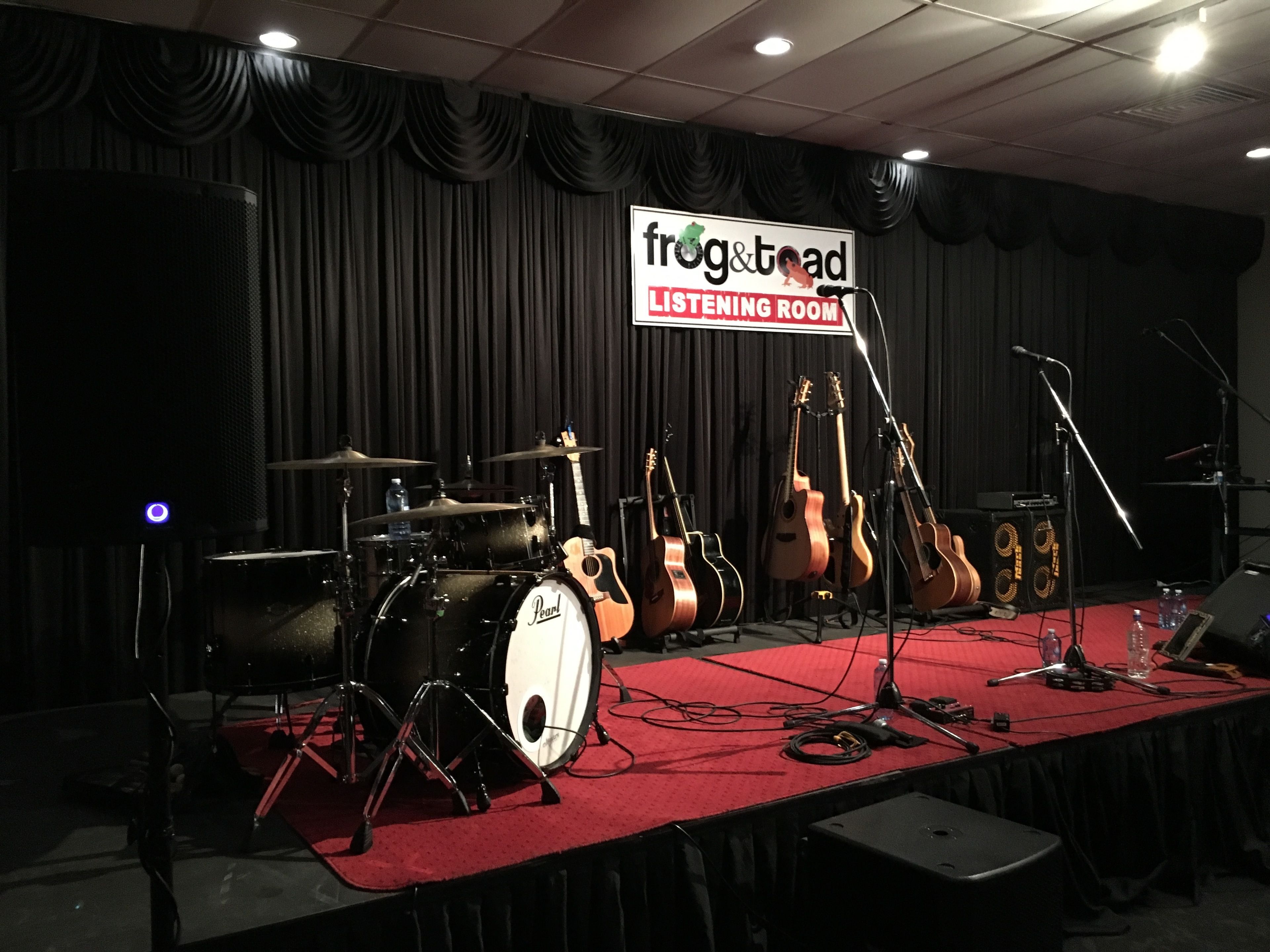 A stage with musical instruments and a sign that reads "frog & toad Listening Room".