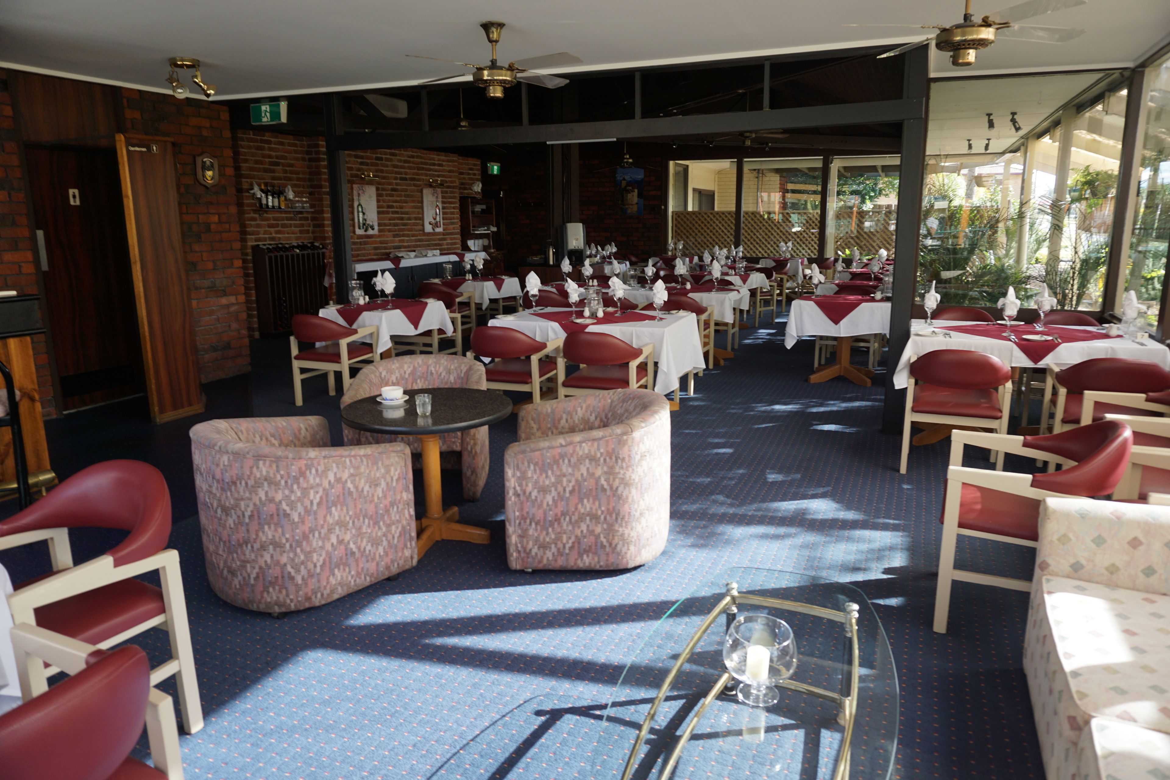 A restaurant with tables and chairs, a patterned sofa, and a ceiling fan.