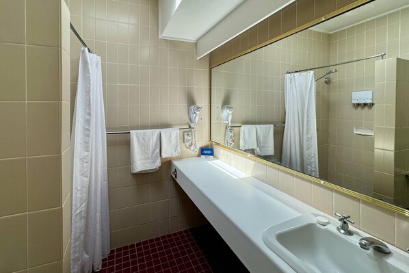 A bathroom with a bathtub, a mirror, a towel rack, and a shower curtain.