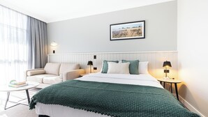 Ein modernes Hotelzimmer mit einem großen Bett, einer Couch, einem kleinen Tisch und einem Bild an der Wand.