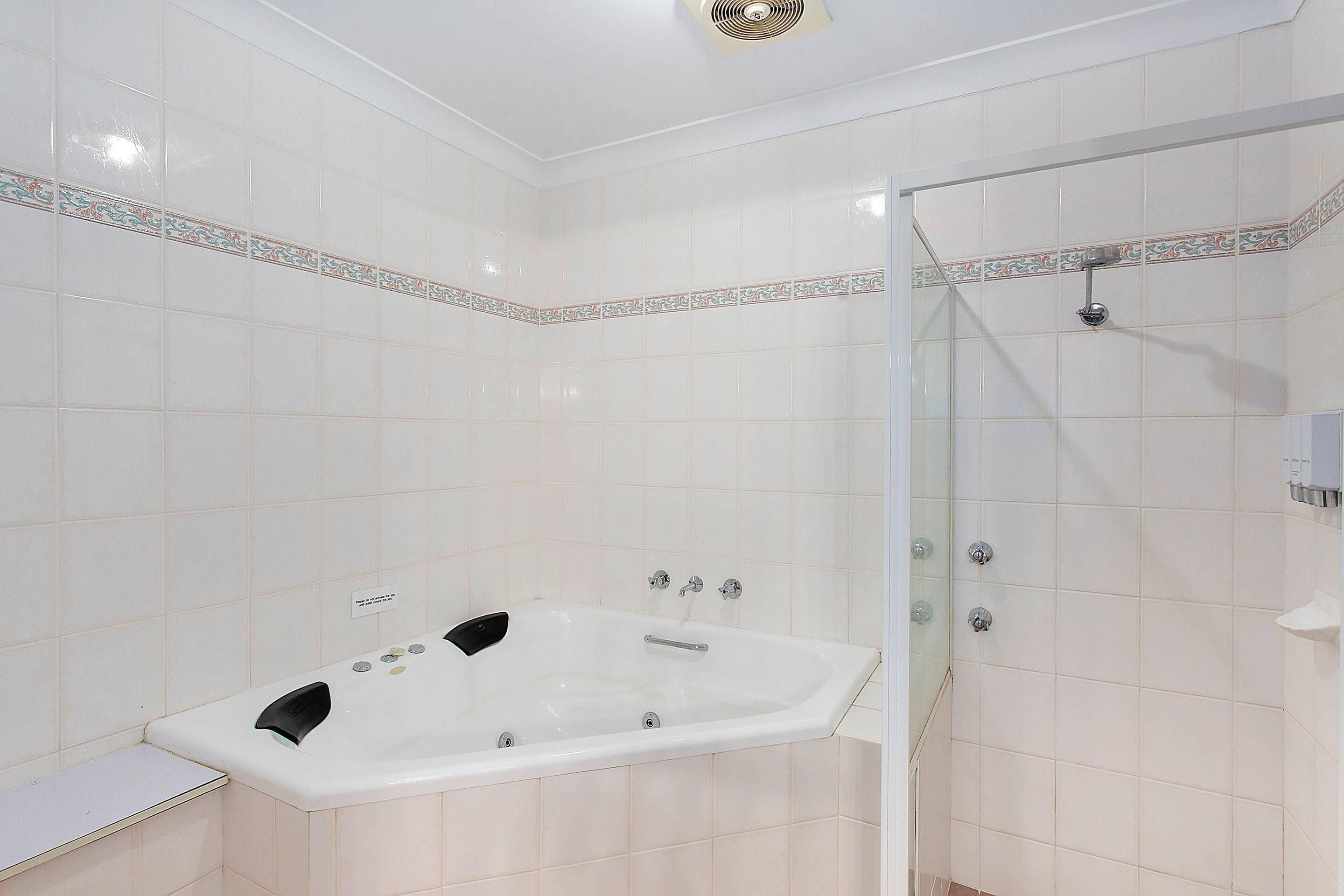 A bathroom with a bathtub, shower, and tiled walls.