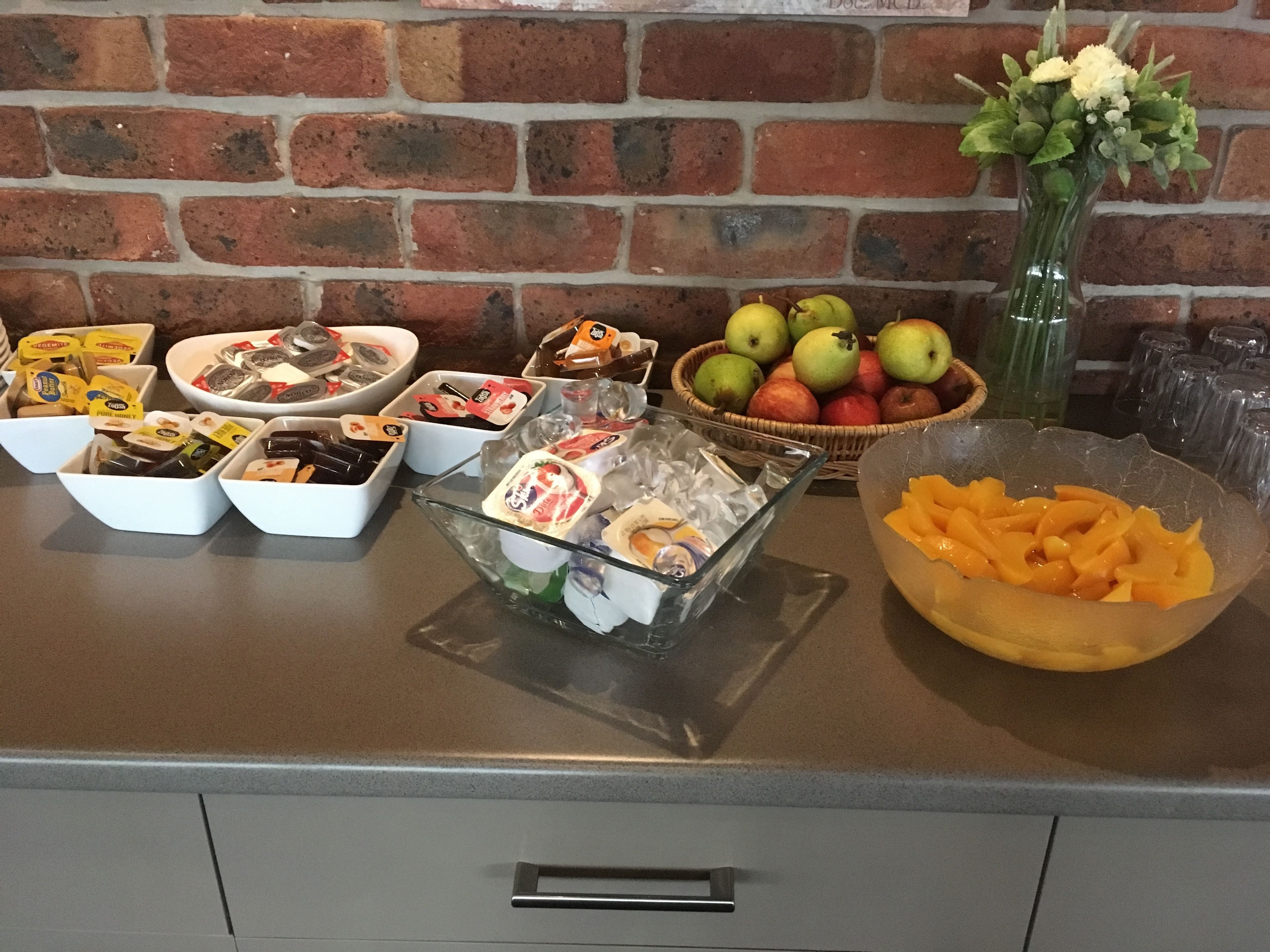 A buffet table with various food items, including fruits, cheeses, and packaged snacks.