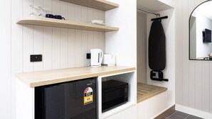 Eine kompakte Küchenzeile mit einem integrierten Kühlschrank, einer Mikrowelle und einer Kaffeemaschine.