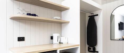 Una kitchenette compacta con refrigerador, microondas y cafetera incorporados.