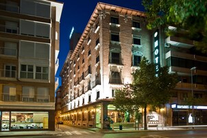 A multi-story hotel with a prominent 'HOTEL' sign, a visible entrance, and a tree in front.
