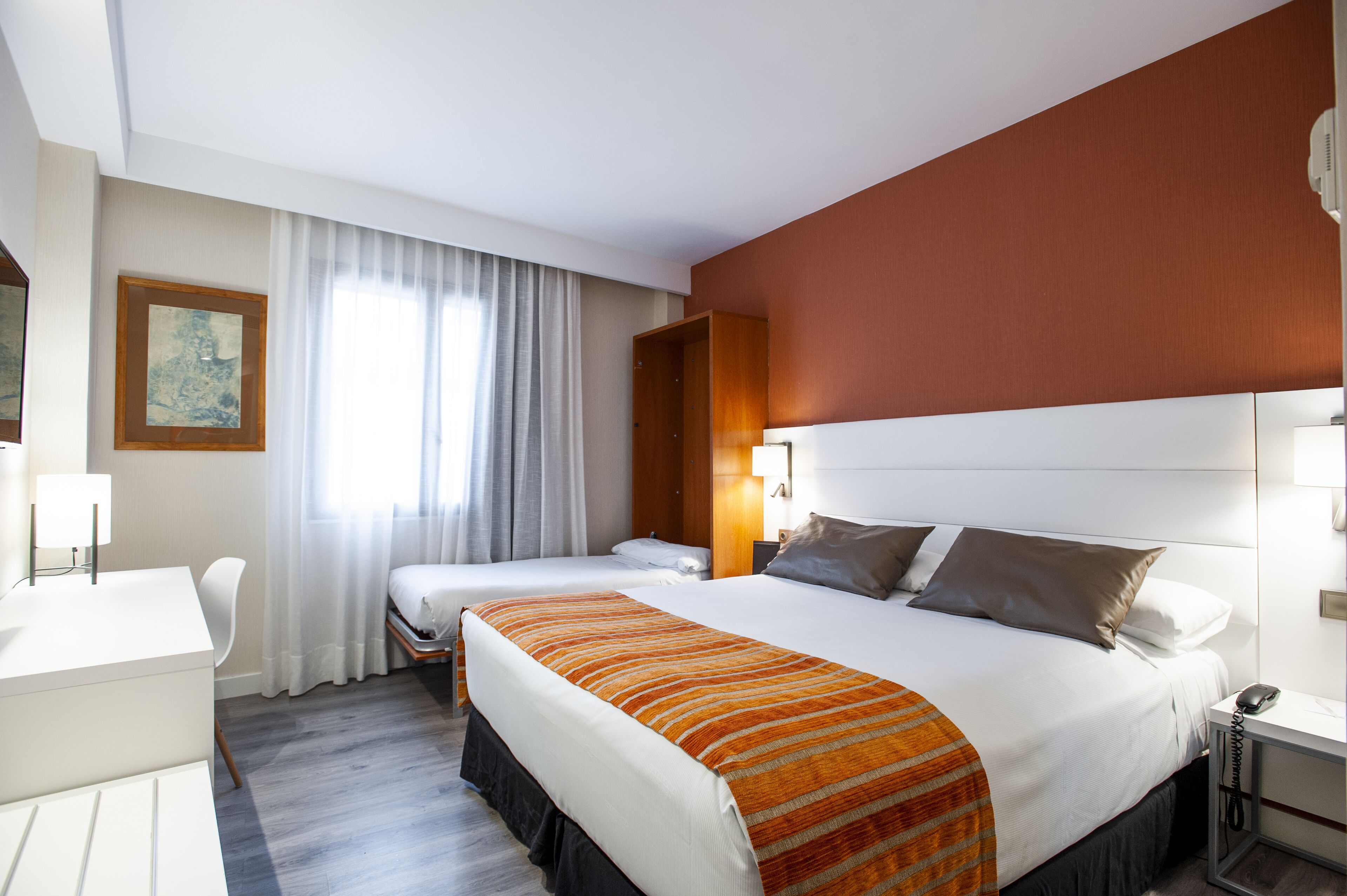 Habitación de hotel con dos camas, un escritorio y una silla.