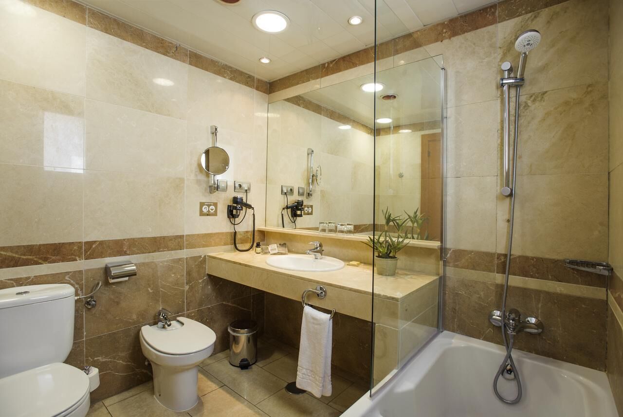 A modern bathroom with a glass-enclosed shower, a sink, a toilet, and a mirror.