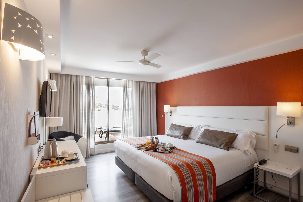 Une chambre d’hôtel avec un lit, une table de chevet, une lampe et une vue sur l’extérieur.