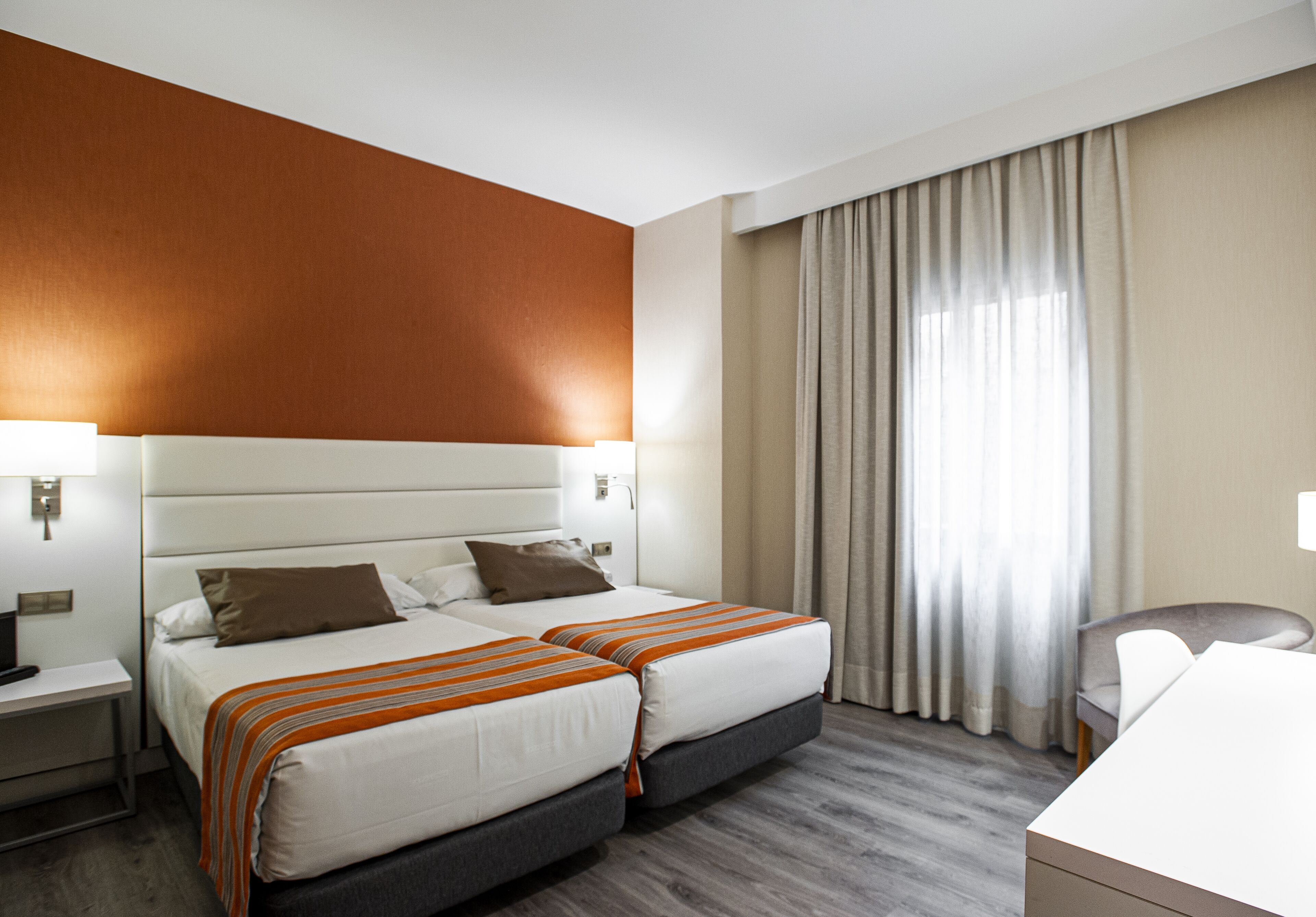 Habitación de hotel con dos camas, un escritorio y una silla.
