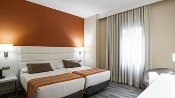 Habitación de hotel con dos camas, un escritorio y una silla.