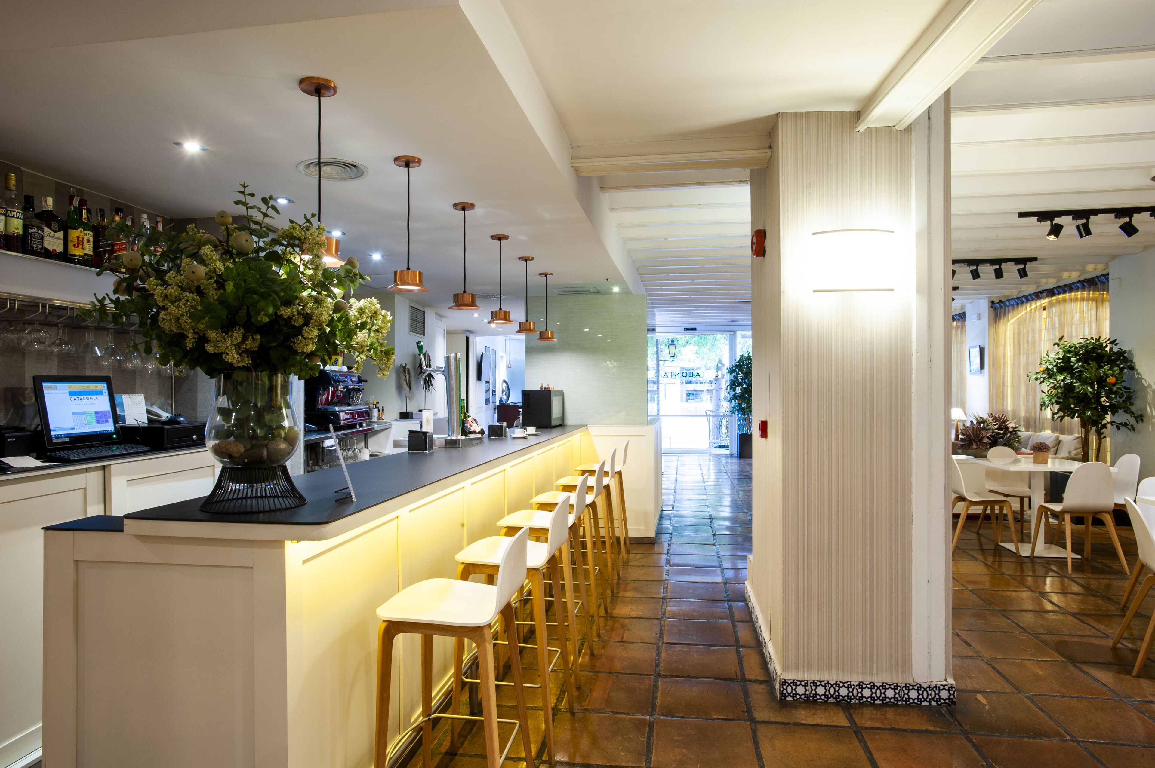 Een moderne bar met een lange toonbank, meerdere barkrukken en diverse flessen op planken.