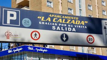 Un panneau indiquant « APARCAMIENTO LA CALZADA », avec le symbole d’un parking ouvert 24 heures sur 24, une interdiction de traversée pour les piétons, une flèche pointant vers le bas et une limitation de vitesse à 20 km/h.