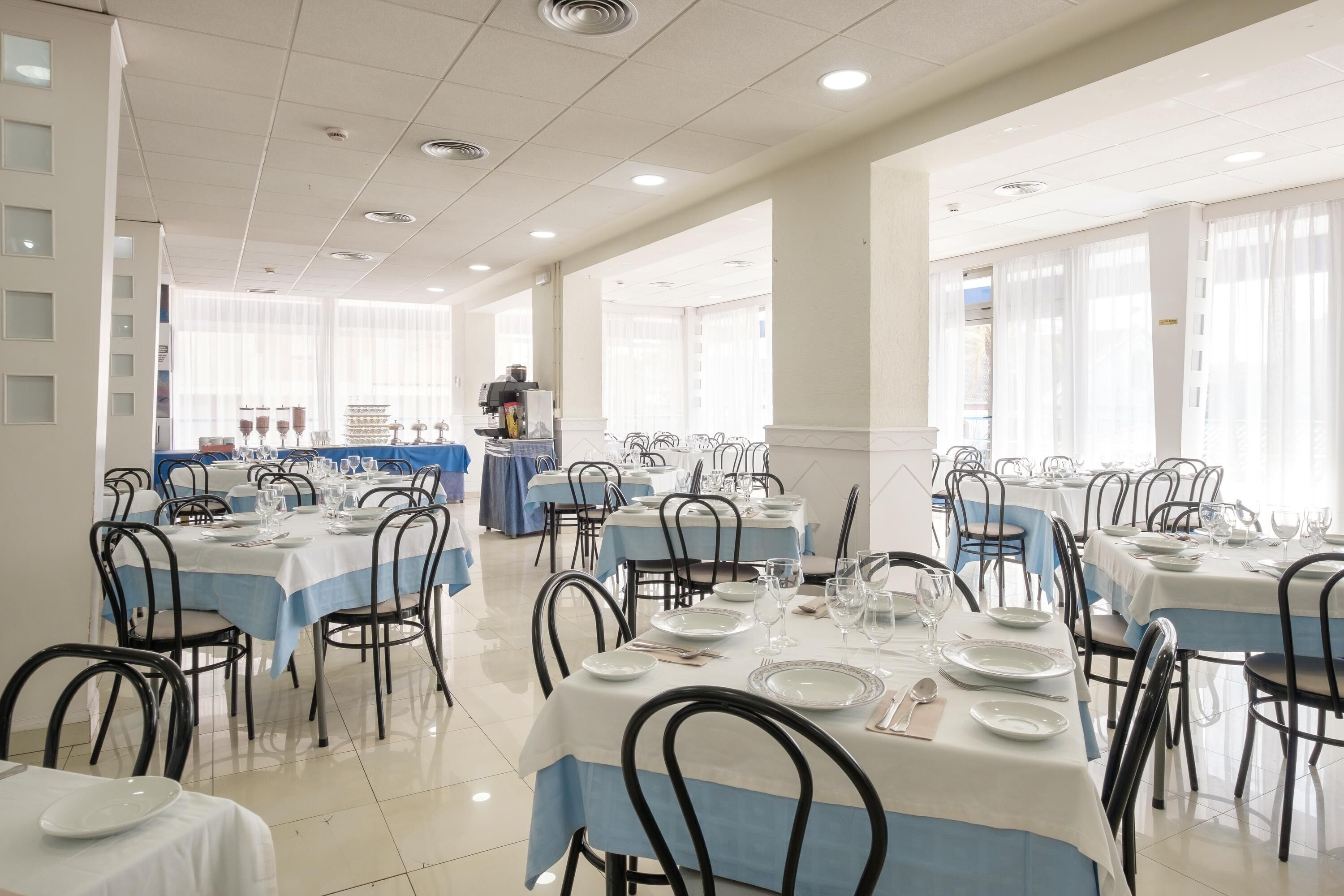 A spacious dining area with multiple tables set for service, featuring a clean and modern design.