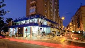 A hotel with a blue facade, multiple floors, and a staircase leading to the entrance.