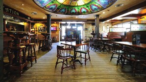 A bar area with wooden furniture, a stained glass ceiling, and a view of the bar counter.