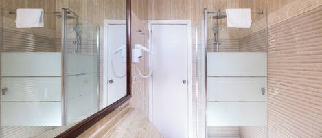 Een moderne badkamer met een douchecabine van glas, een witte deur en een marmeren aanrechtblad.