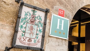 A building facade with a coat of arms sign and a sign with the letter "H".