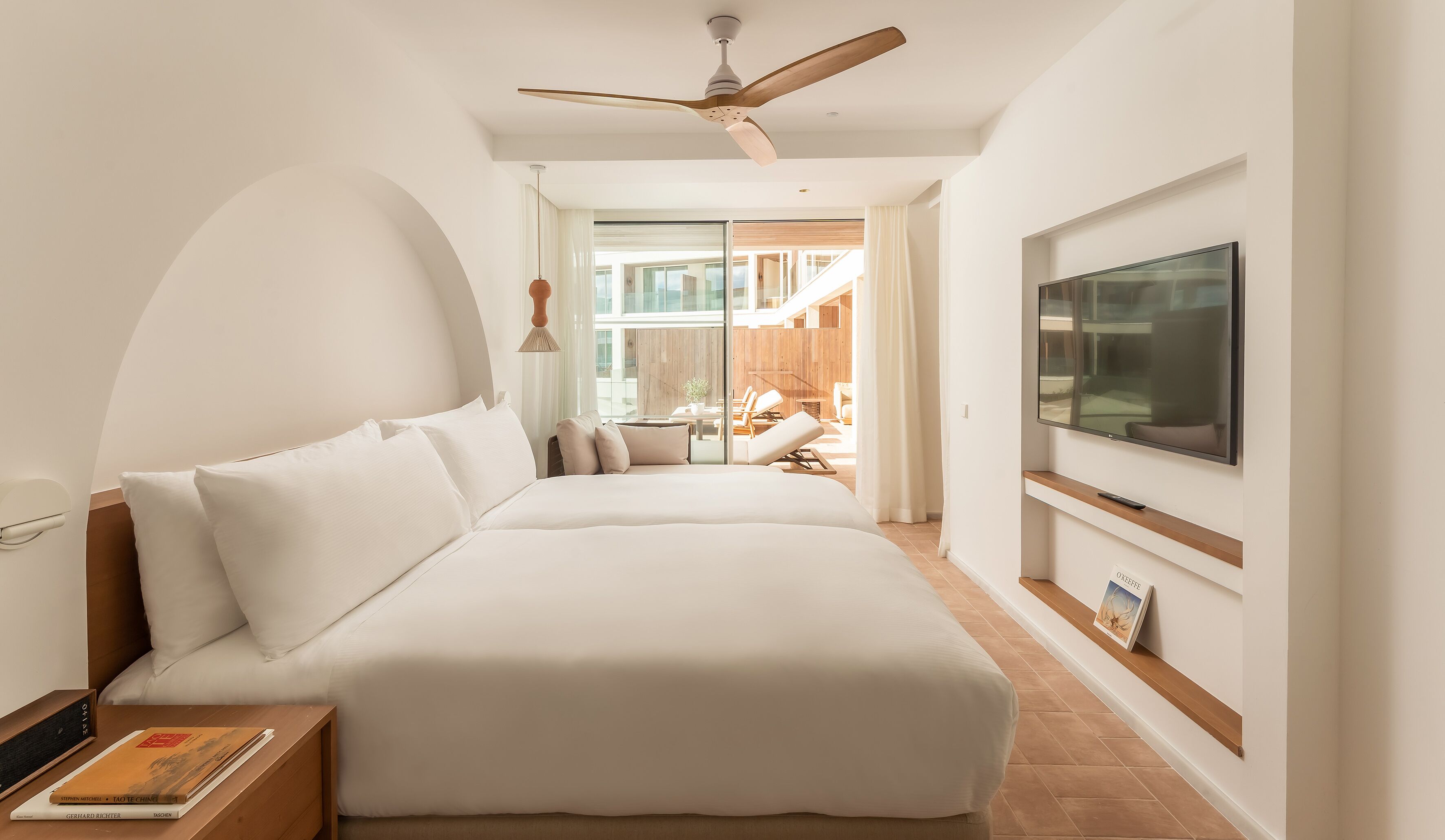 Ein modernes Hotelzimmer mit einem großen Bett, einem Fernseher und Blick auf den Außenbereich.