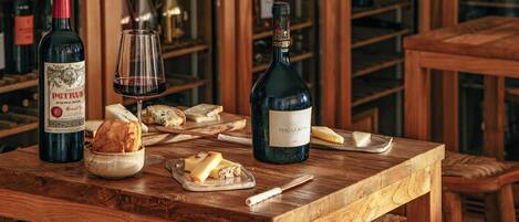 A wooden table with wine bottles, glasses, and cheese.