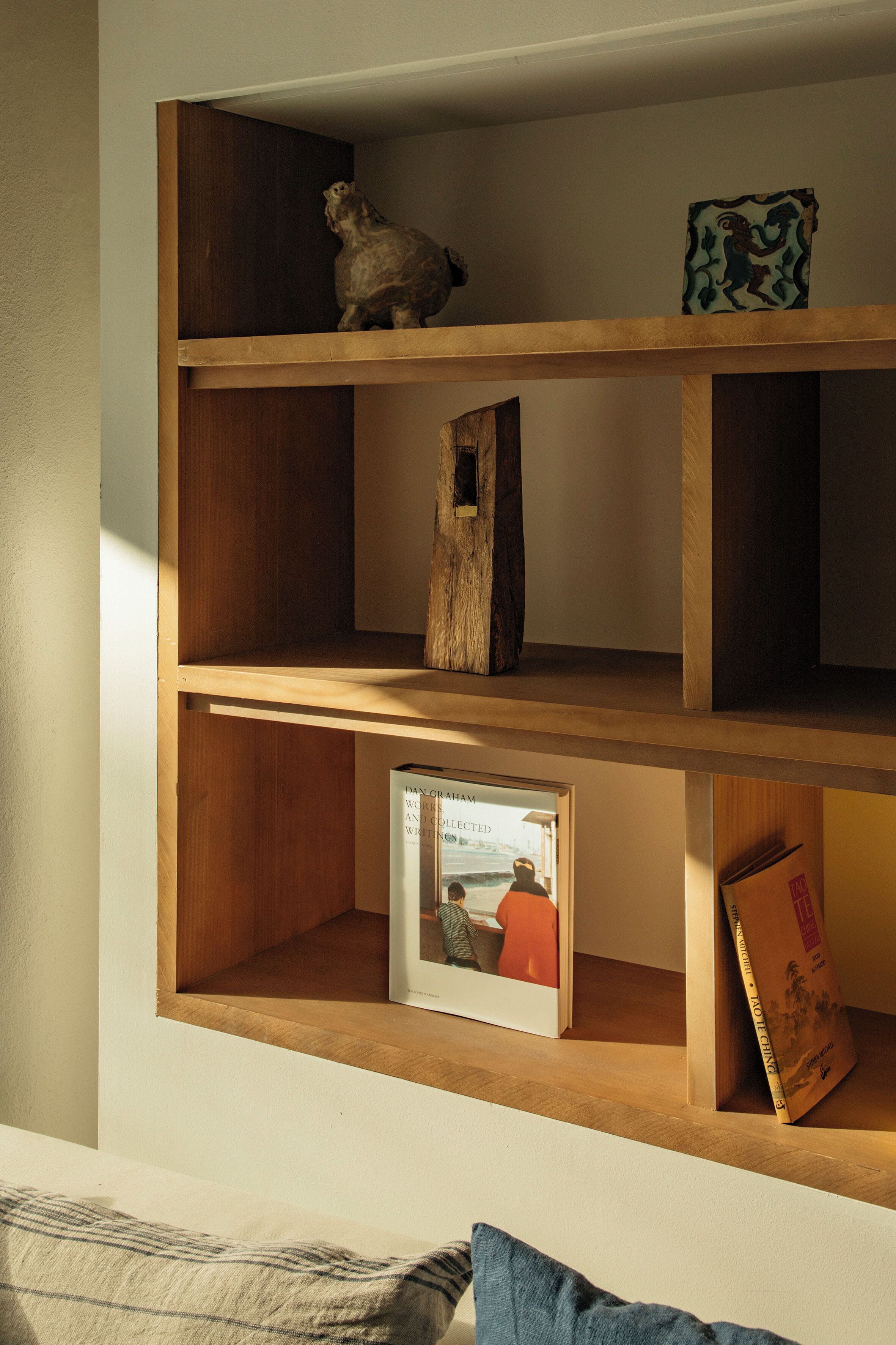 Una estantería de madera con diversos objetos, incluyendo un cuadro enmarcado, un libro y una pequeña escultura.