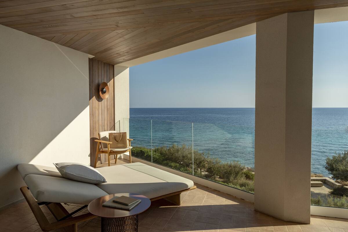 Un balcon moderne avec vue sur la mer, un canapé, un fauteuil et une petite table.