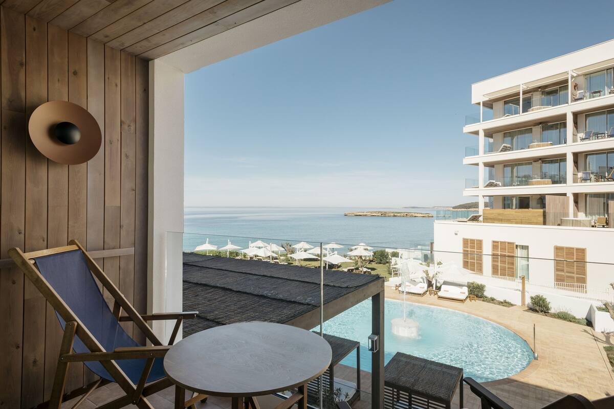 Un balcon avec vue sur la mer, une piscine et un immeuble à plusieurs étages.