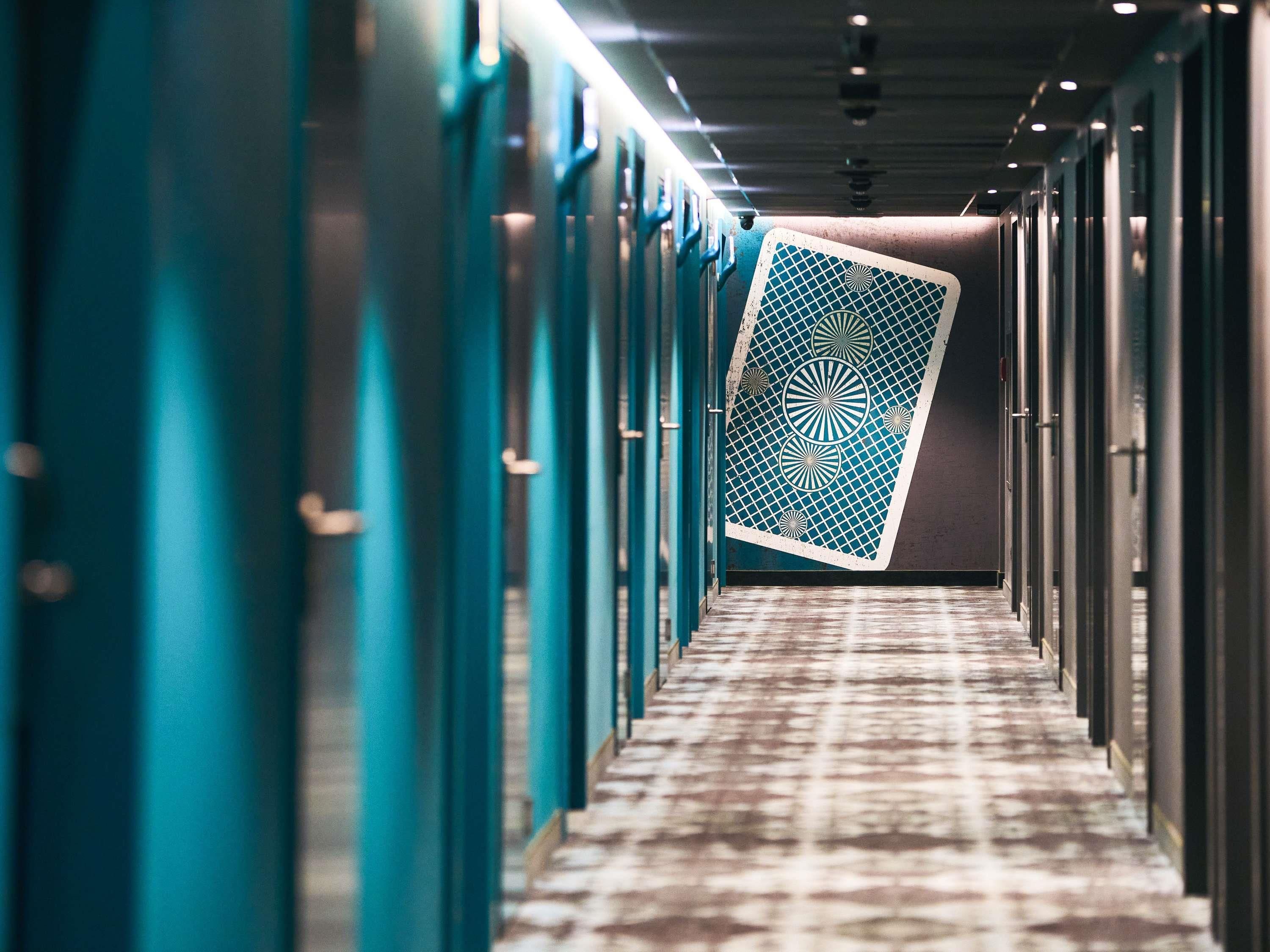 Un pasillo con puertas color turquesa y suelo estampado.