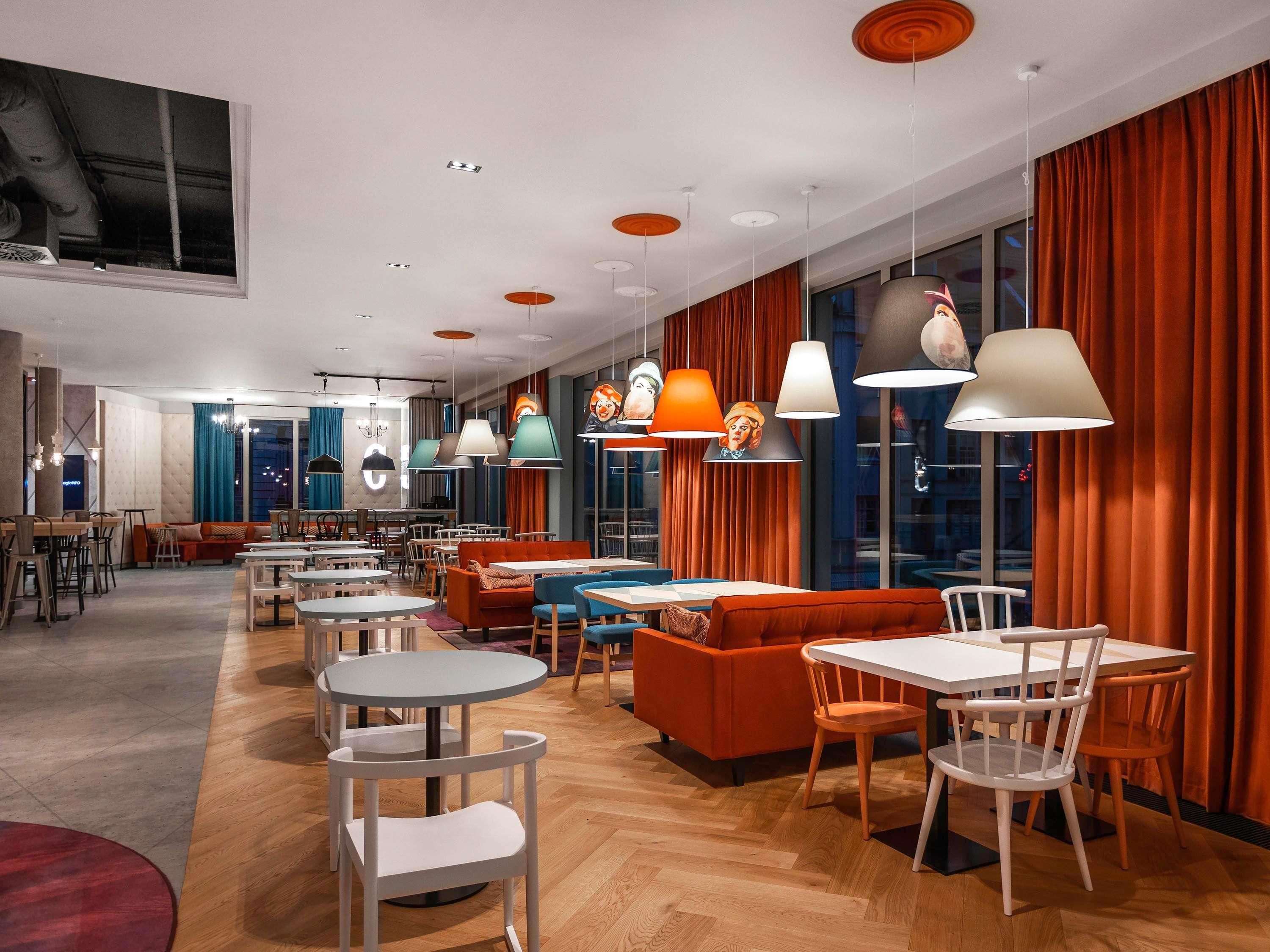 A modern interior with multiple seating areas, tables, and pendant lighting.