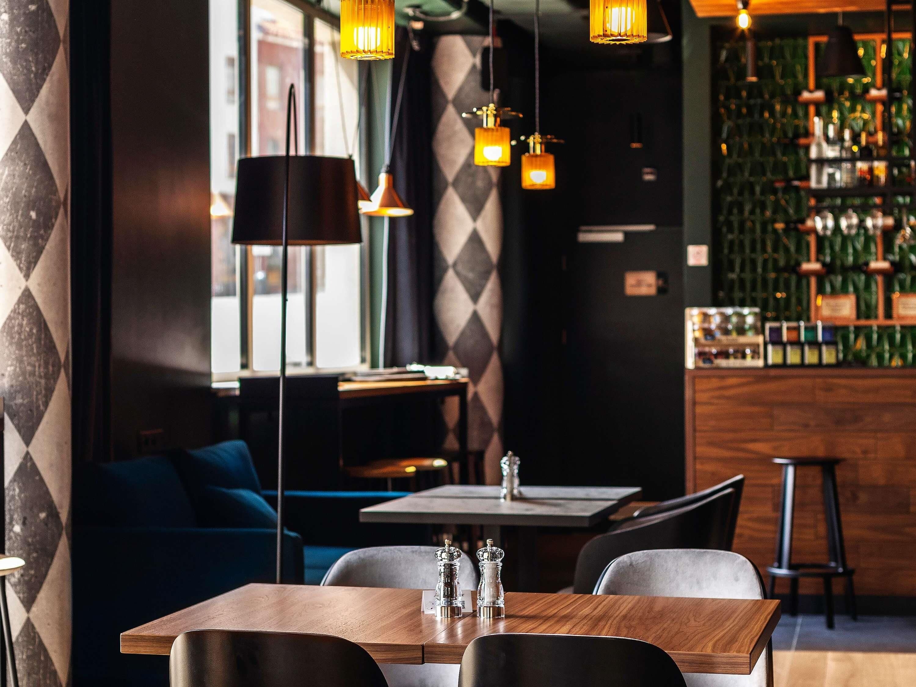 A restaurant interior with a bar area, seating, and pendant lighting.