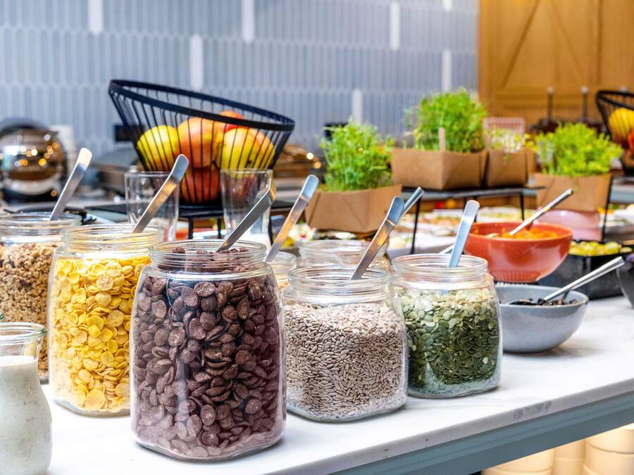 A buffet with various food items in jars and bowls, including cereals, nuts, and seeds.