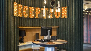 A reception area with a 'RECEPTION' sign, a desk, a computer, and two stools. - ibis Styles Szczecin Stare Miasto (Szczecin)