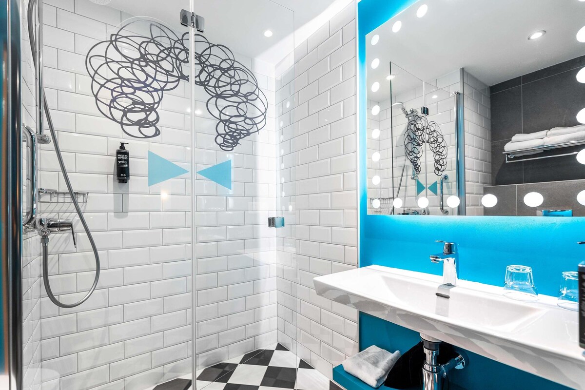 A modern bathroom with a shower, a sink with a mirror, and a checkered floor.