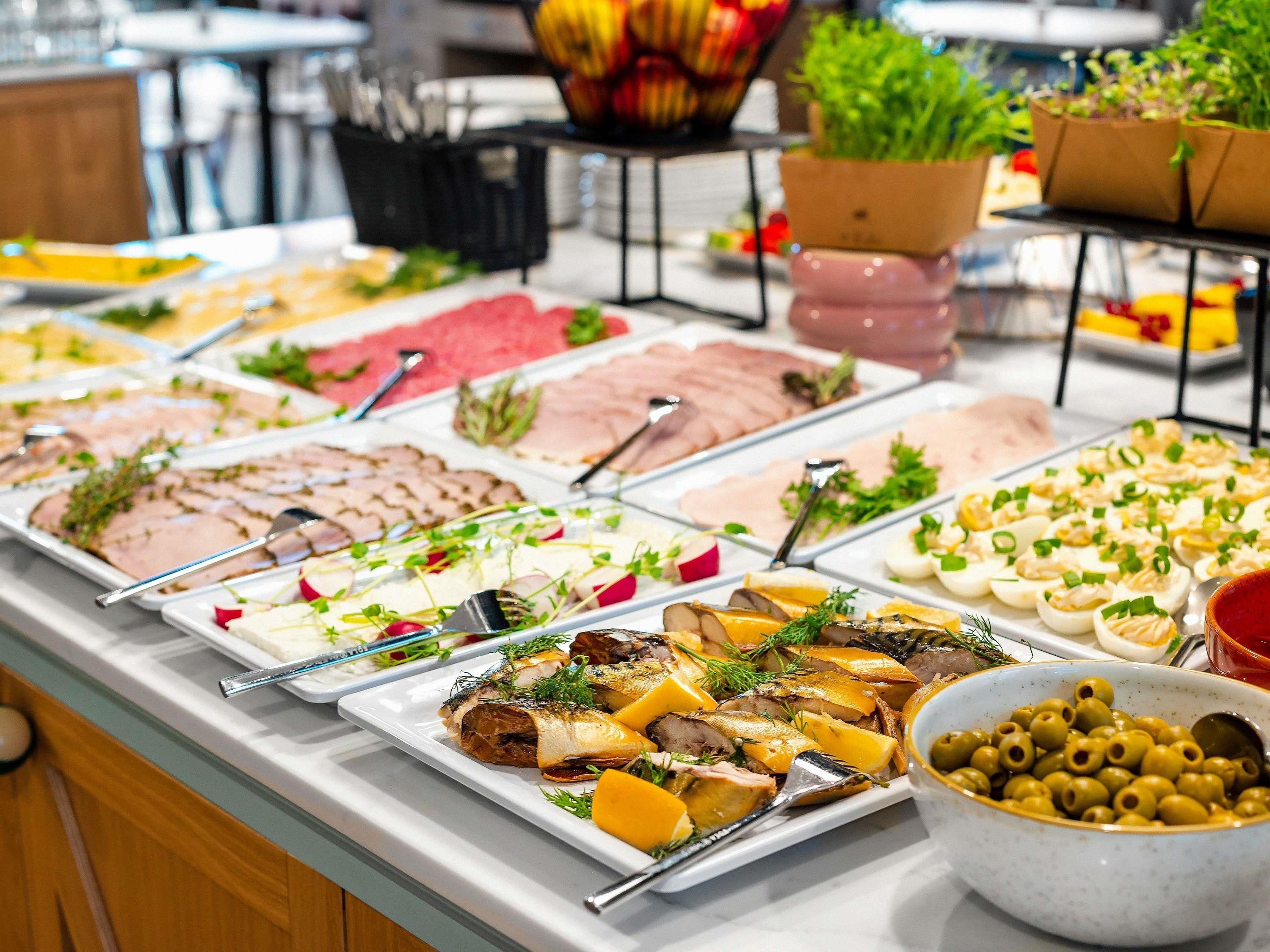 A buffet with various food items and a bowl of olives.