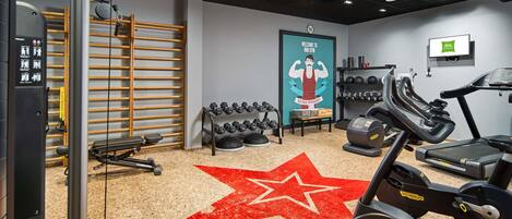 A gym with exercise equipment, a star-patterned carpet, and a welcome sign.