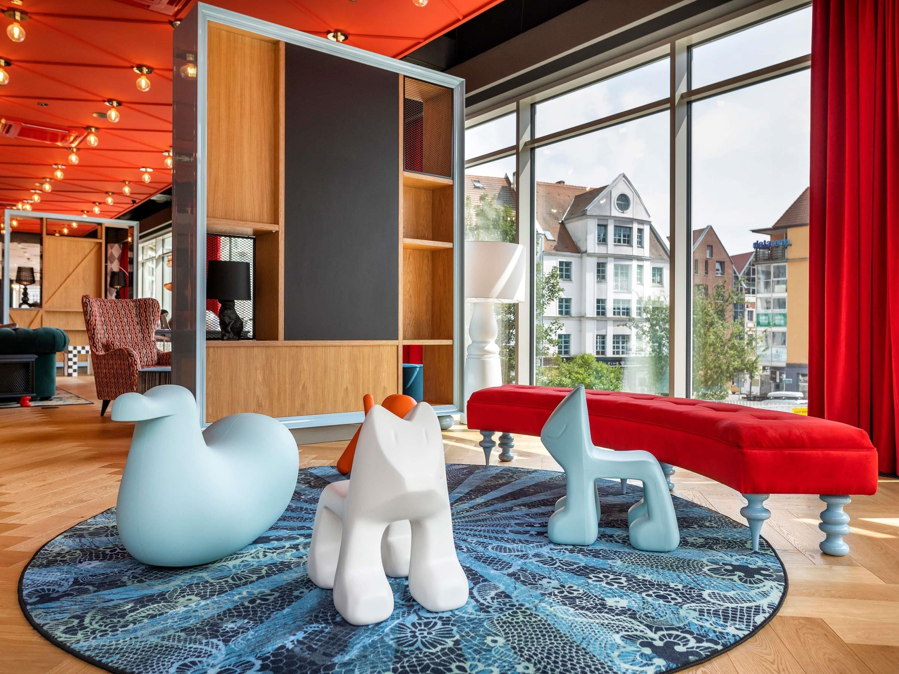 Een modern interieur met een groot raam, een rode bank en bijzondere stoelen in dieren vorm.